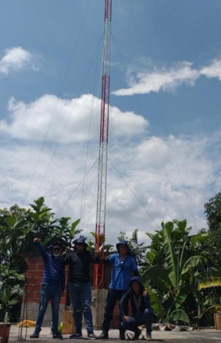 Equipo de WIFIMAX NETWORK junto a una torre de telecomunicaciones
